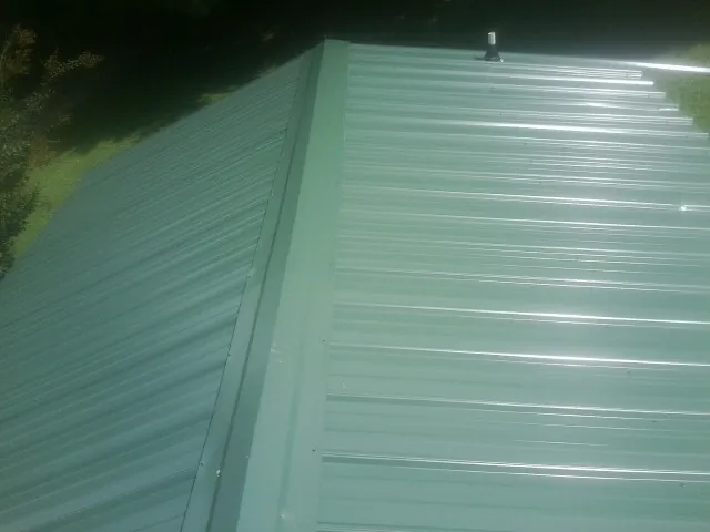 New green metal panels meeting at the ridge of a roof — Flat Roof Repair work by our crew in Columbia City