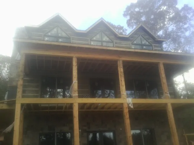 Dormers and porch framing on a large log home under construction — Roof Coating work by our crew in Columbia City