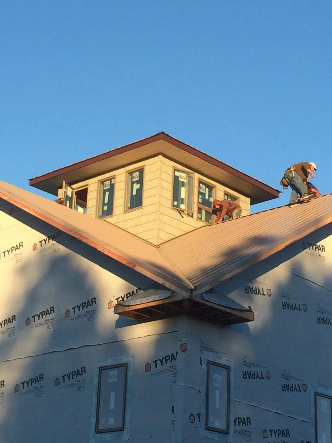 Roofers working around a rooftop cupola on a new metal roof at sunset — Roof Waterproofing in Columbia City by Roofing Brothers